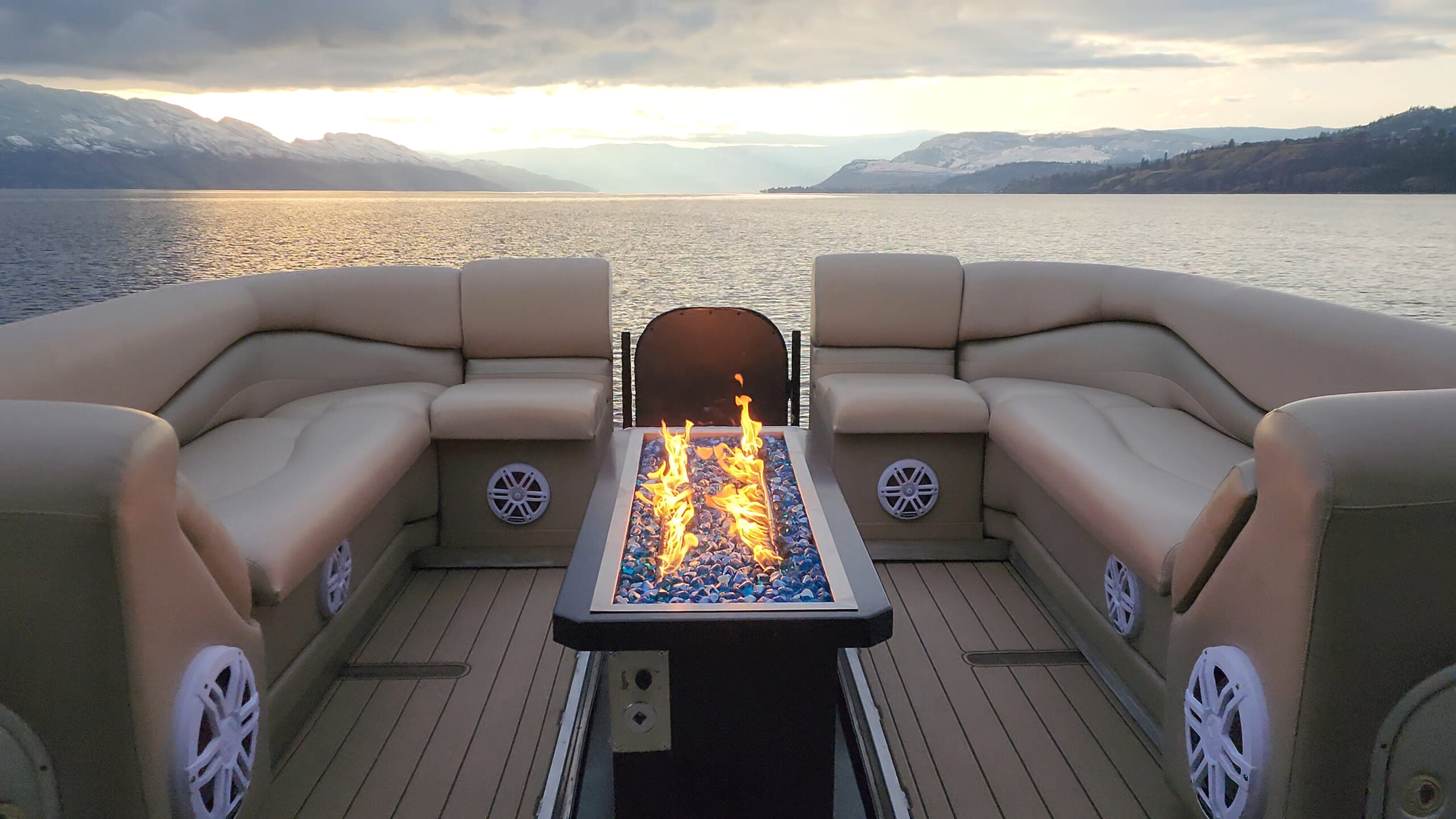 Balanced wide bow lounge, glowing fire pit and sunset lake view.