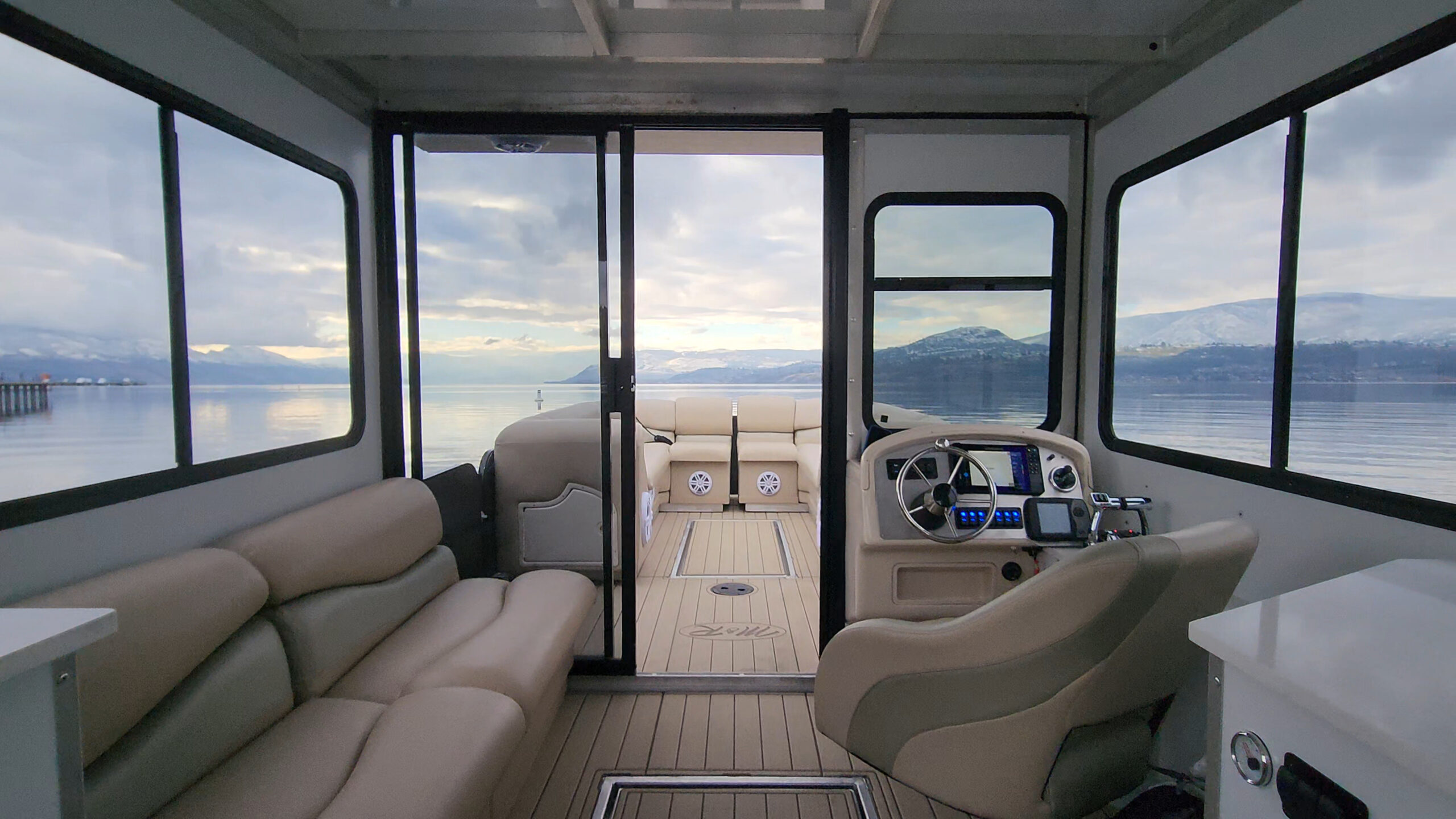 Wide cabin view with enclosed seating, helm and forward deck doorway.