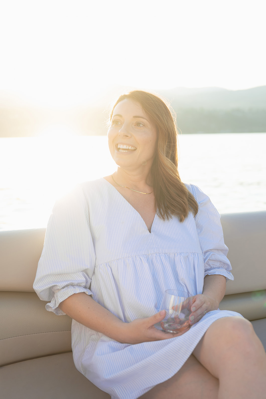A guest in a pale blue dress holds a glass in the evening light.