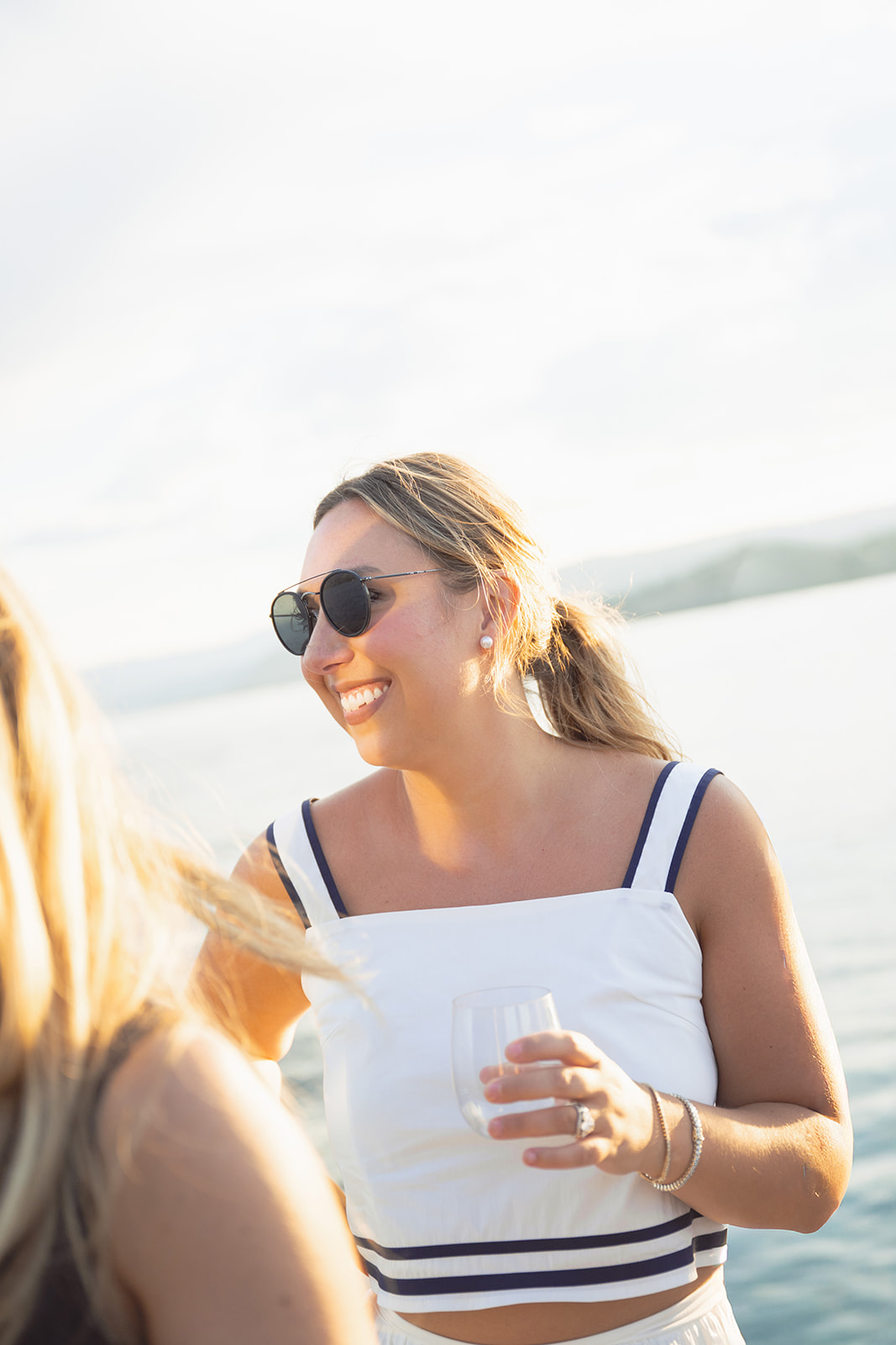 A guest in a white nautical top smiles while holding a glass.