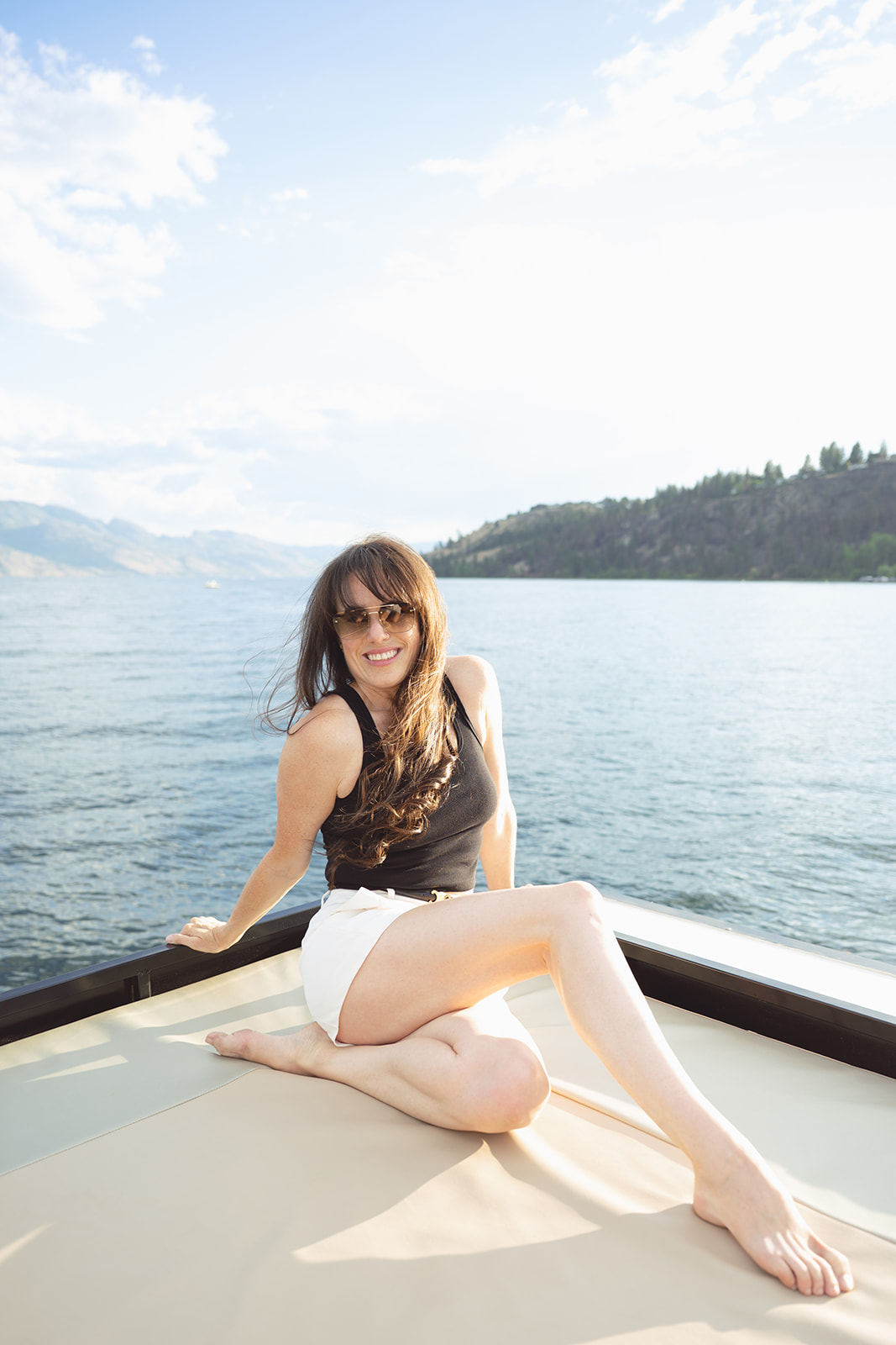A guest smiles from the rooftop sun bed with the lake behind her.