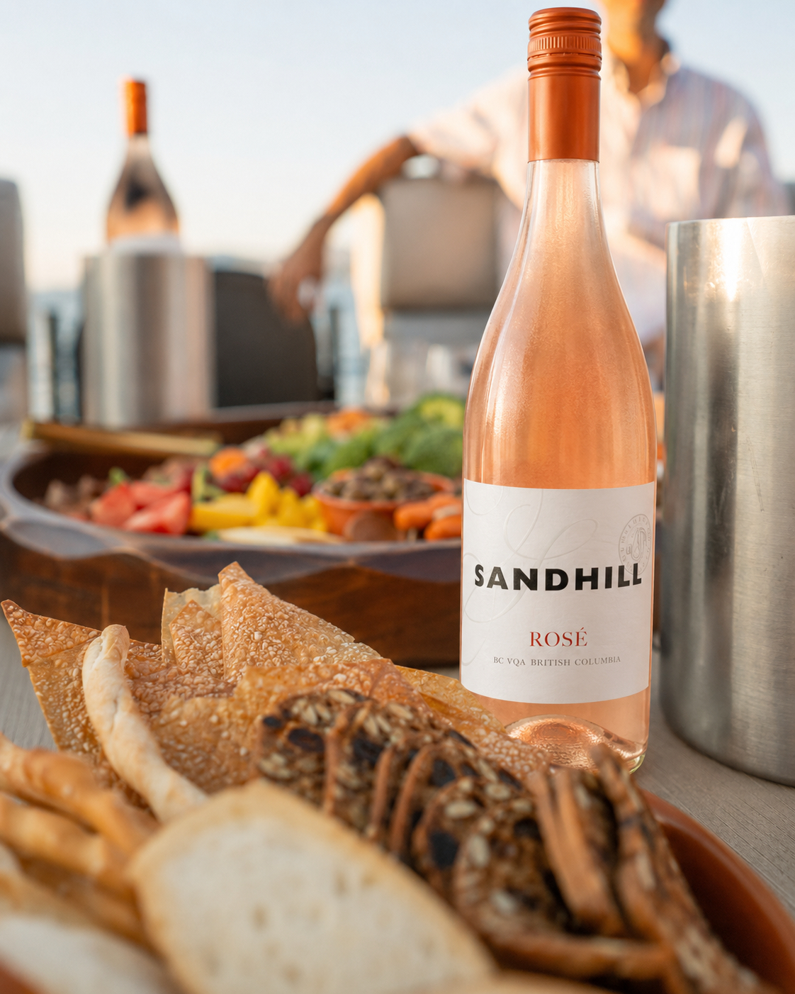Sandhill rose bottle stands beside bread and a charcuterie spread on board.