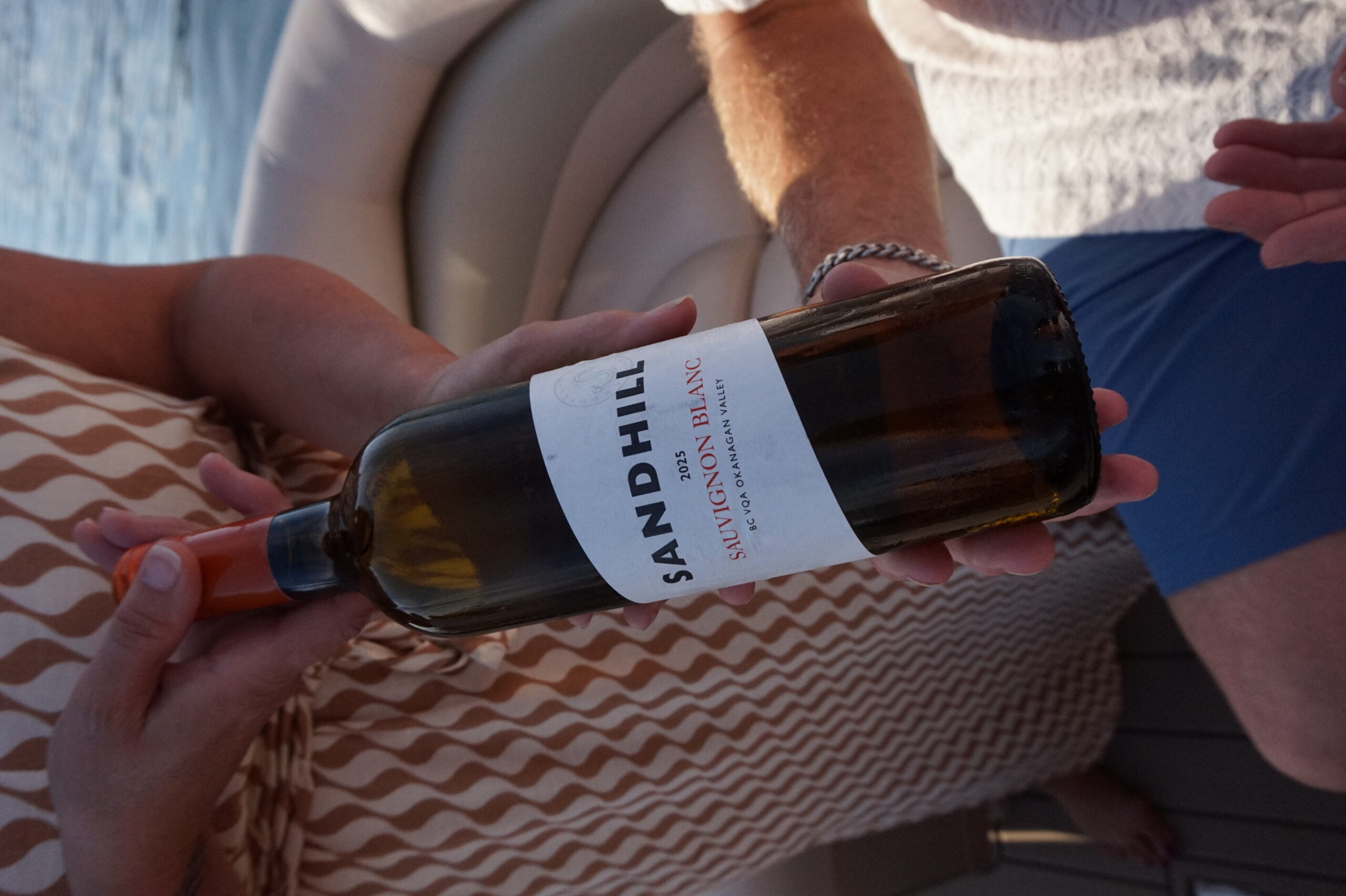 Hands present a Sandhill Sauvignon Blanc bottle with its label readable.